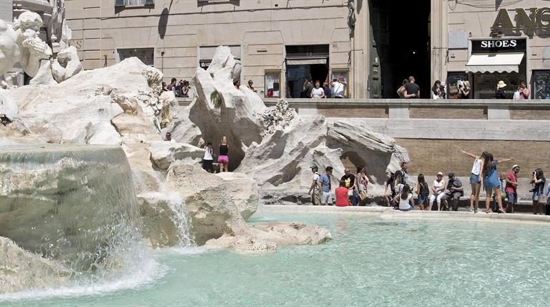 Varios turistas se hacen fotos en la Fontana di Trevi, en Roma.